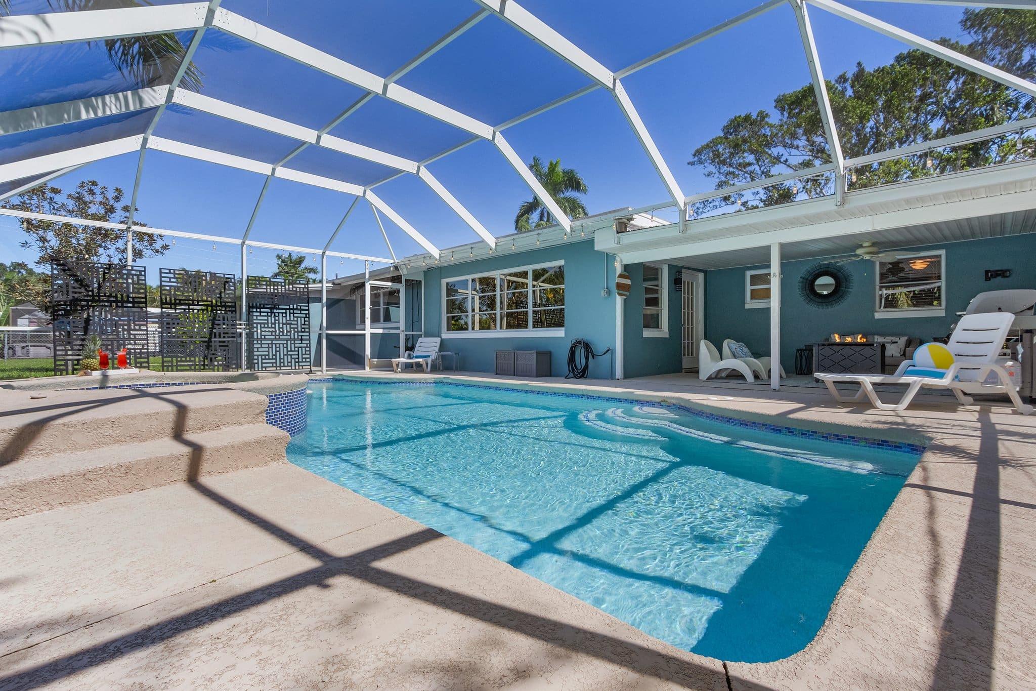 Spacious screened-in backyard with in-ground pool, lounge seating, and covered patio area in a tropical Florida home