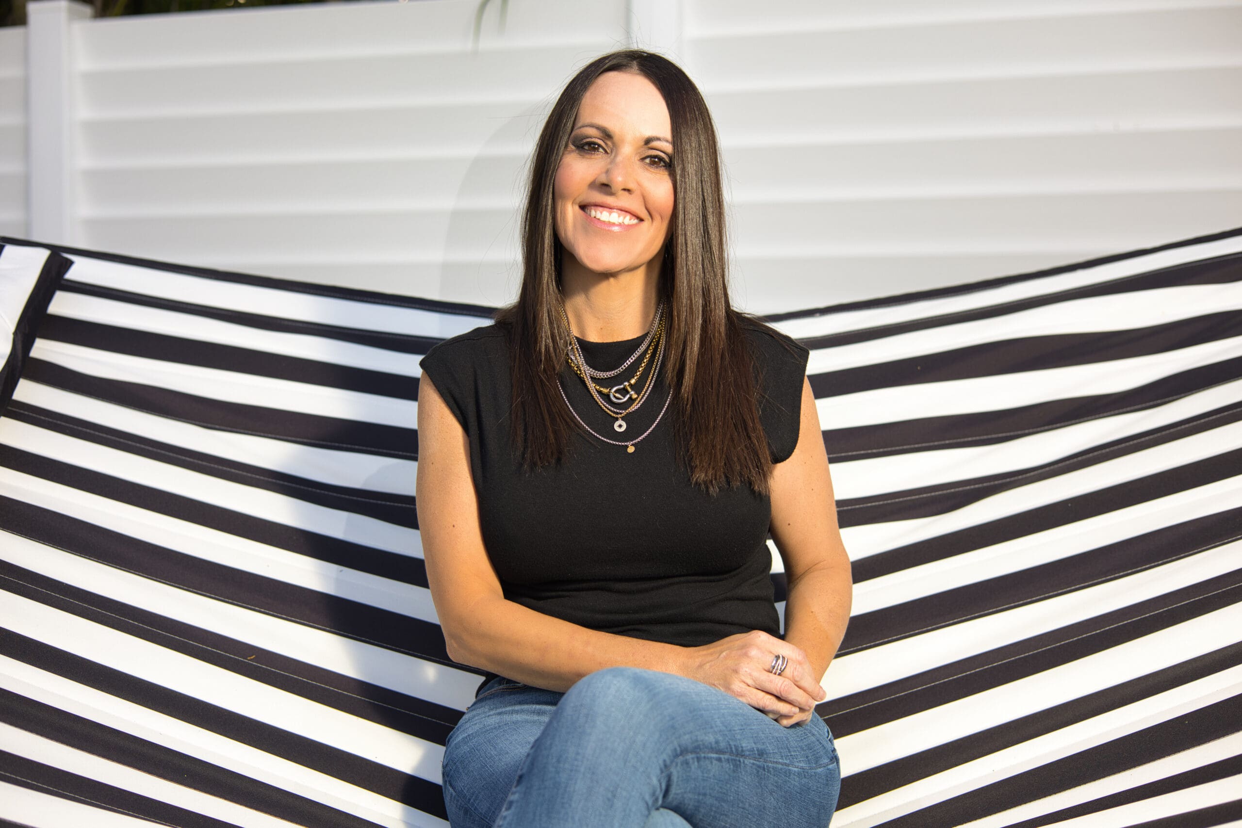 Friendly and approachable photo of Shari Casanova in jeans and a black top, highlighting her brand’s vibe.